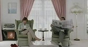 couple sitting in a clean white living-room, reading